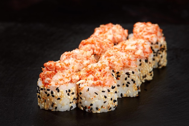 Warm rolls with tuna salmon perch eel tobiko caviar nori rice cucumber on a black background