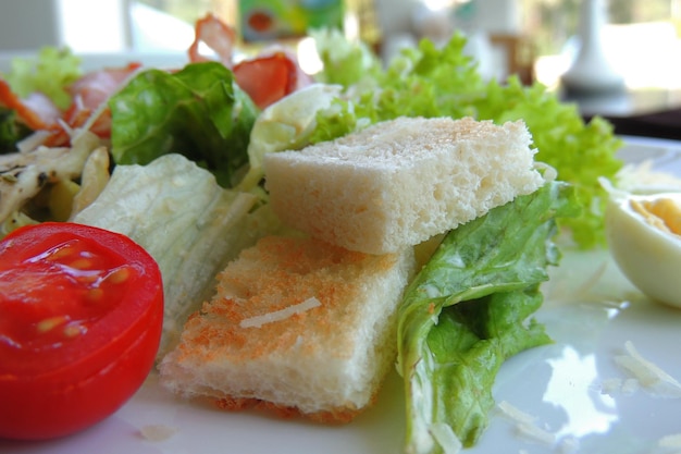 Warm salad with chicken, greens and white bread toast closeup side view