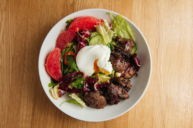 Warm salad with grilled chicken liver in white plate