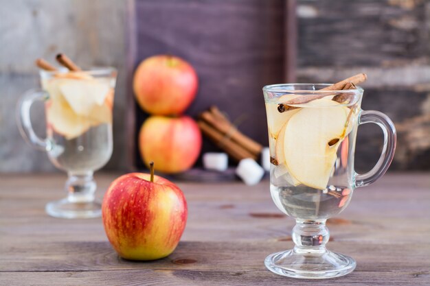 Warm soothing tea made from apples and cinnamon in glasses and ingredients for cooking on a wooden table. Detox concept, antidepressant. Beautiful still life