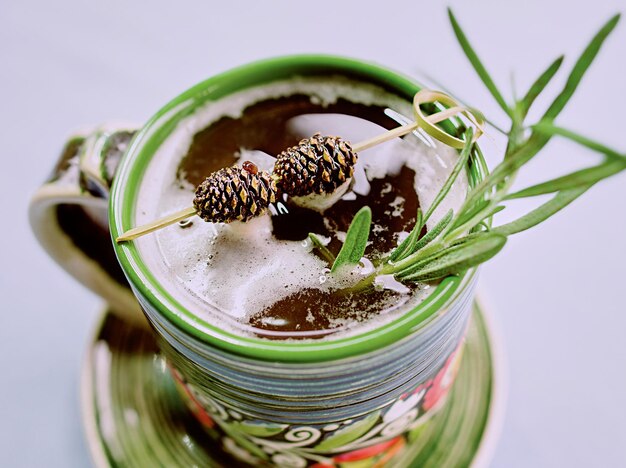 Warm strong alcohol cocktail with syrup with rosemary and bump on a top in the cup