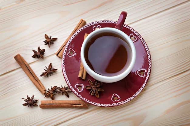 Warm tea in the red cup on the wooden table