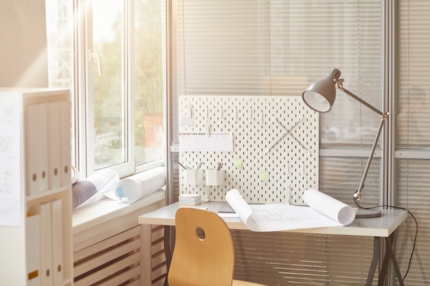 Warm-toned background image of engineers workplace lit by sunlight, 