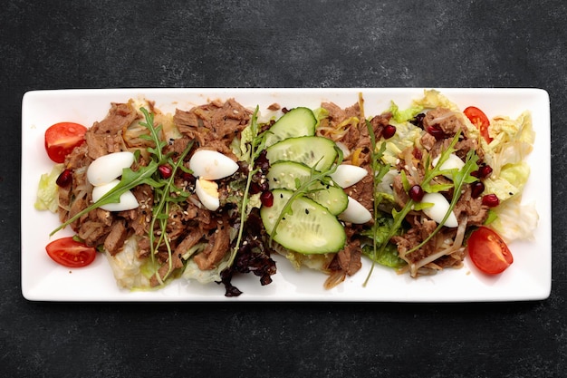 Warm veal salad with fresh vegetables quail eggs and lettuce leaves