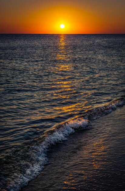 Warm waves of the Mediterranean sea and a sandy beach at sunrise