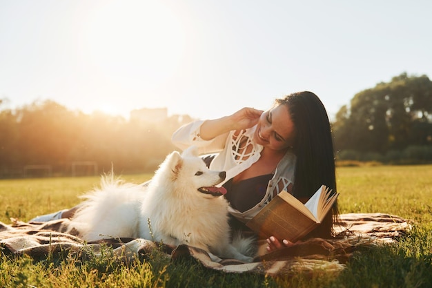 따뜻한 날씨 그녀의 강아지와 함께 여자는 화창한 낮에 들판에서 재미