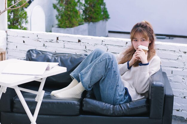 Warm Winter Girls Sitting on the Sofa Reading and Drinking Coffee