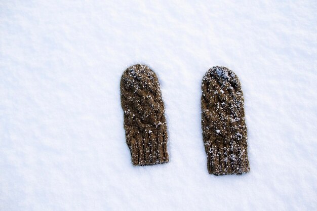 Warm woolen mittens lying on the white snow frosty day at sunset View from above