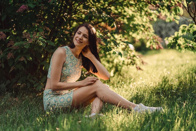 Warm zonnig portret van een aantrekkelijk donkerbruin meisje onder de lila in het licht van de zon.