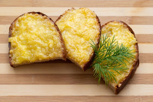 Foto warme boterhammen met gesmolten kaas en kruiden op een houten achtergrond