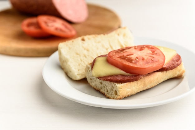 Warme broodjes met gesmolten kaasworst, salami en tomaten