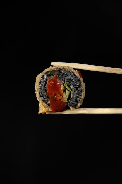 Warme broodjes met zwarte rijst Sushi met rode vis rijst garnalensla op een zwarte ondergrond Roll in sticks