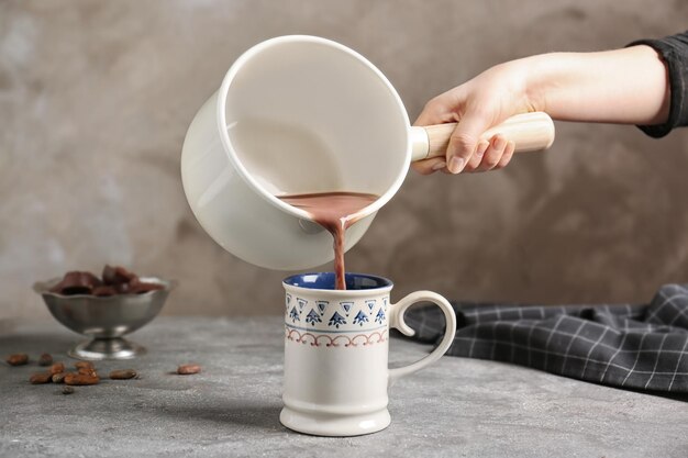 Warme cacaodrank in de beker op de keukentafel gieten