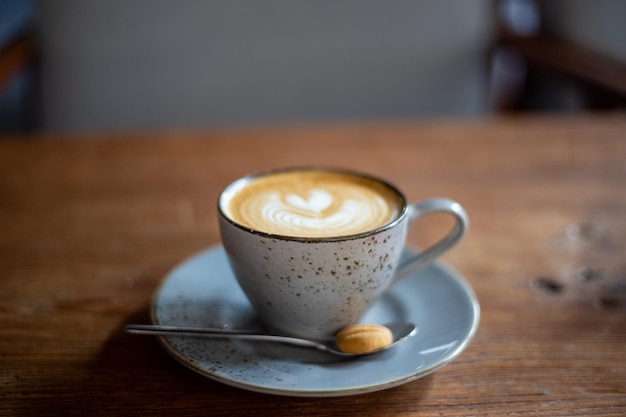 Warme cappuccino-koffiekop met hartvorm latte art op bruine oude houten tafel in café