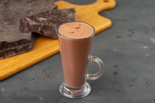 Warme chocolademelk drinken in glazen beker en chocoladereep