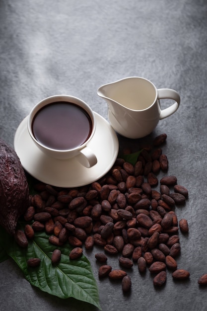 Warme chocolademelk en cacaopoeder snijden de cacaobonen bloot op een donkere tafel