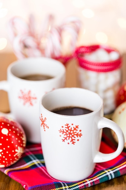 Warme chocolademelk in witte kopjes met rode sneeuwvlokken.