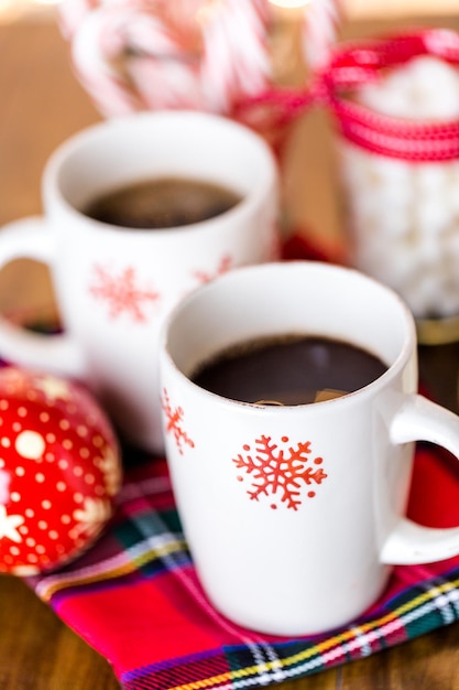 Warme chocolademelk in witte kopjes met rode sneeuwvlokken.