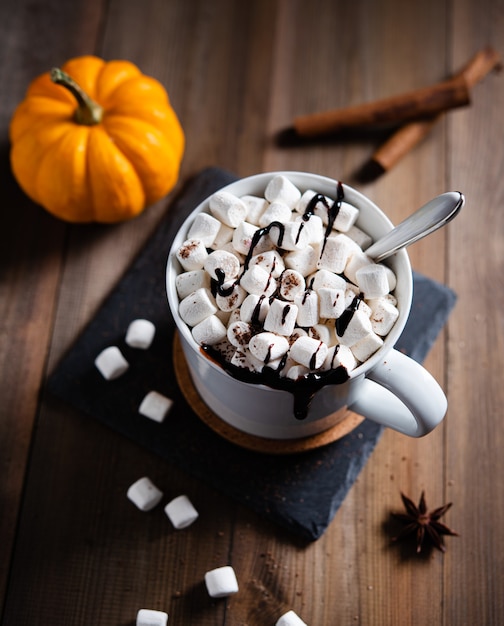 Warme chocolademelk met marshmallow en kaneel in een witte mok op een houten tafel. Bovenaanzicht