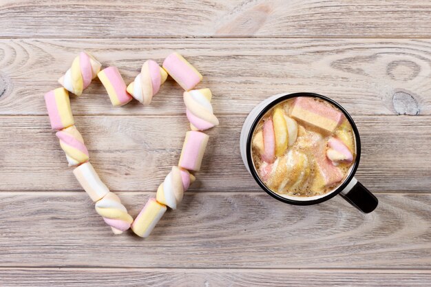 Warme chocolademelk met marshmallow in hartvorm. warme cacao met marshmallows. Kop warme chocolademelk met marshmallows op de houten tafel