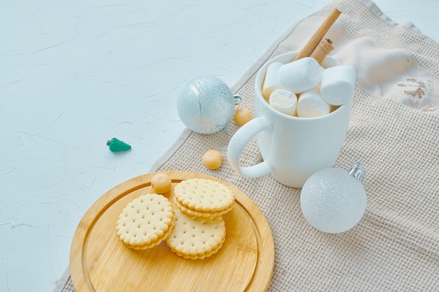 Warme chocolademelk met marshmallows en kaneelkoekjes op dienbladtafelkleed op witte tafel het concept van...