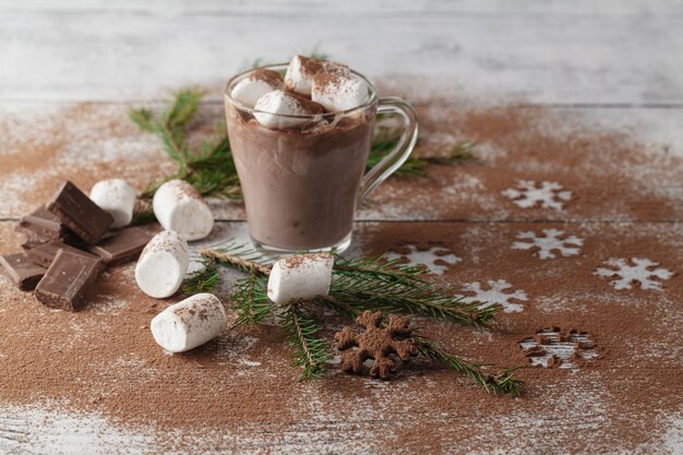 Warme chocolademelk met marshmallows en kerstdecoratie op witte houten tafel