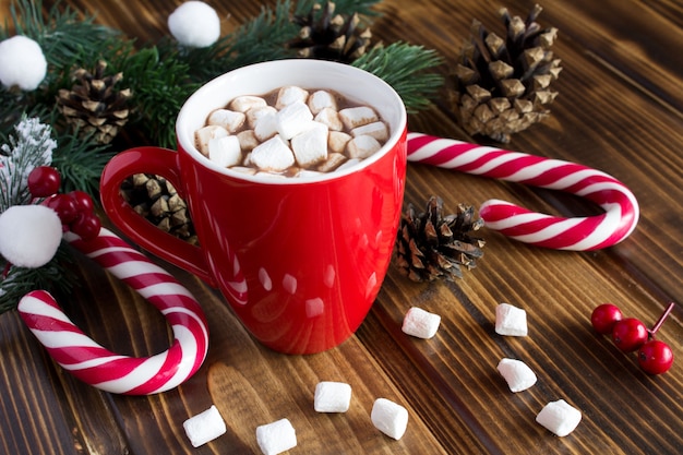 Warme chocolademelk met marshmallows in de rode kop op de houten achtergrond