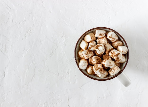 Warme chocolademelk met marshmallows in een witte mok op een witte achtergrond. Recepten.