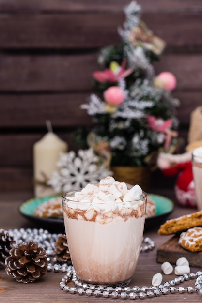 Warme chocolademelk met marshmallows in glazen op een houten tafel met kerstversiering