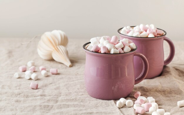 Warme chocolademelk met marshmallows in mokken op een linnen tafelkleed met kerst speelgoed concept van winter h...