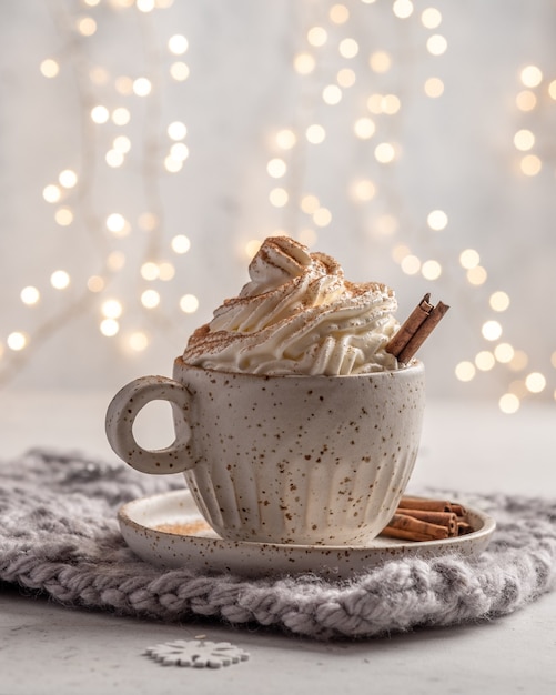 Warme chocolademelk met room en kaneelstokje in een ceramische kop.