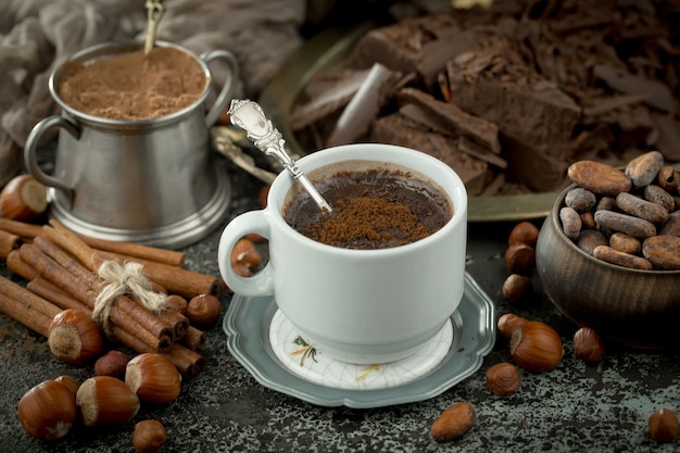 Warme chocolademelk op een oude achtergrond in een compositie met cacaobonen en noten.