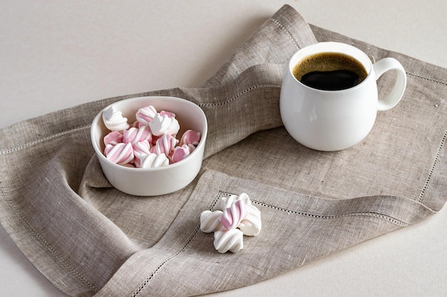Warme geurige koffie en zoete marshmallow in een witte kom op een linnen servet Horizontale foto