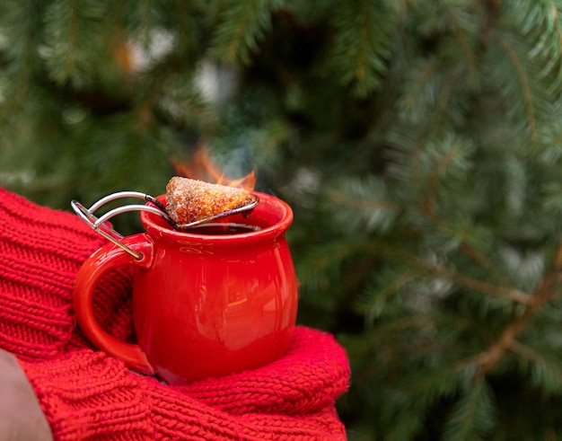 warme glühwein met een brandend stuk suiker op de achtergrond van een kerstboom