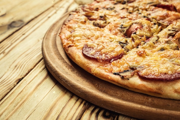 Warme heerlijke zelfgemaakte pizza slice met smeltende kaas op een rustieke houten tafel klaar voor Eat