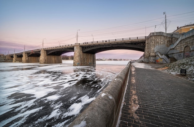 Warme kleuren van koude avond boven de brug over de bevroren rivier in Tver