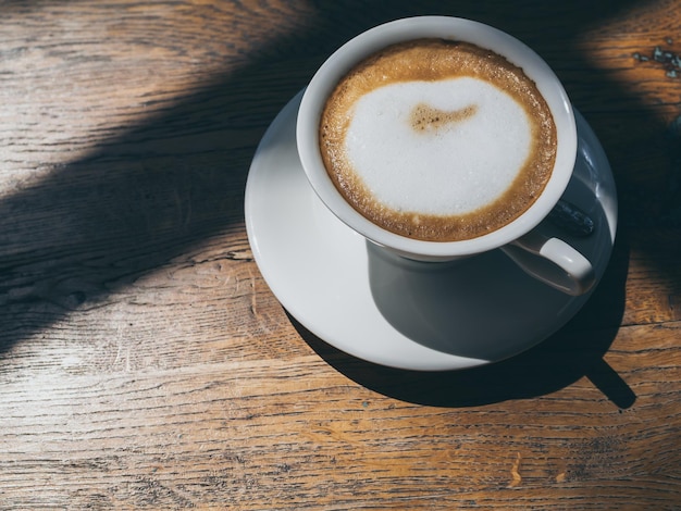 Warme koffie in ronde witte keramische beker op houten tafel achtergrond