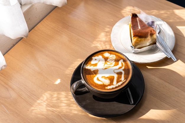 Warme koffie latte met latte art in de vorm van een paardenmelkschuim in bekermok en zelfgemaakte chocoladetaart op houten bureau op bovenaanzicht Als ontbijt In een coffeeshop in het caféduring zakelijk werkconcept