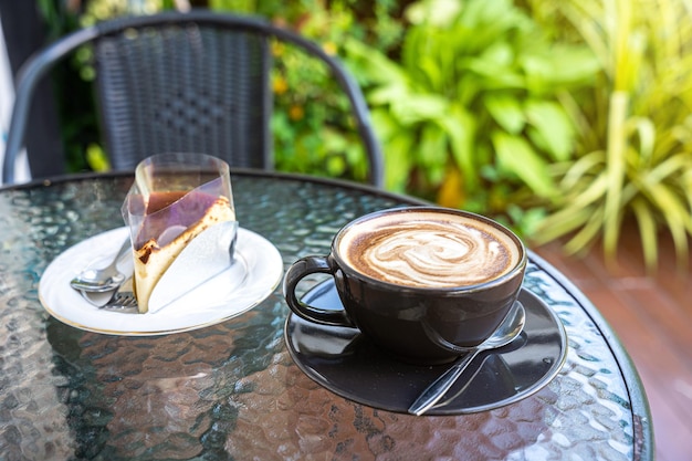 Warme koffie latte met latte art melkschuim in bekermok en zelfgemaakte chocoladetaart op houten bureau op bovenaanzicht als ontbijt in een coffeeshop in het caféduring zakelijk werkconcept