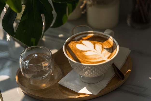 Warme koffie latte met latte art melkschuim in bekermok op houten bureau op bovenaanzicht Als ontbijt In een coffeeshop in het caféduring zakelijk werkconcept