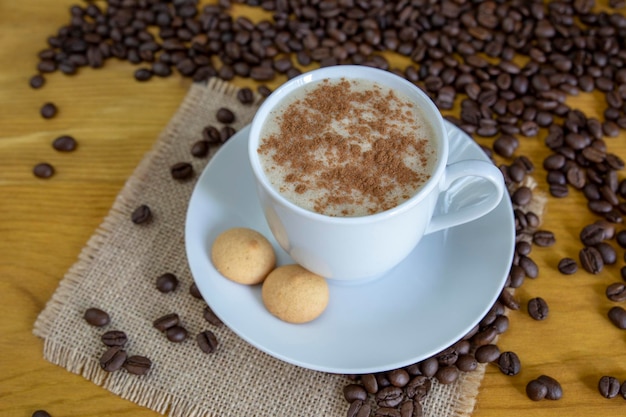 Warme koffie met kaneel met geroosterde koffiebonen op houten achtergrond