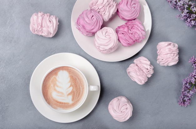 Warme koffie met roze marsmallow op grijze achtergrond