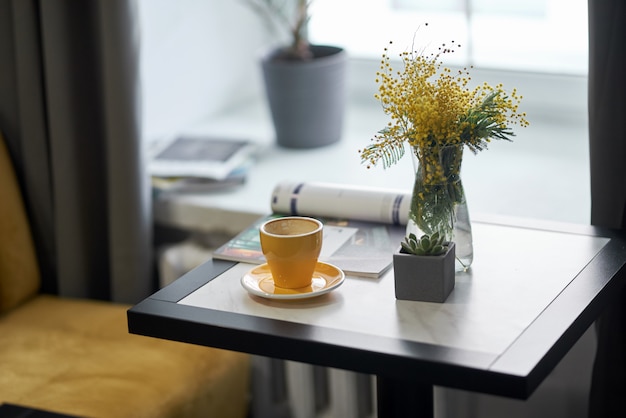 warme koffie vers dagboek, bloemmimosa bij het raam in het café