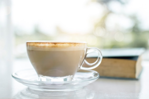 Warme kop koffie met boek op balkon van venster