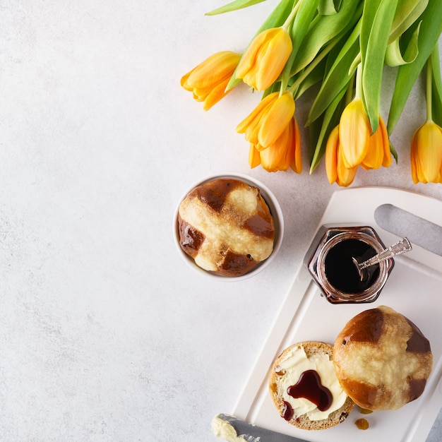 Foto warme kruisbroodjes, boter en jam voor het paasontbijt en tulpen