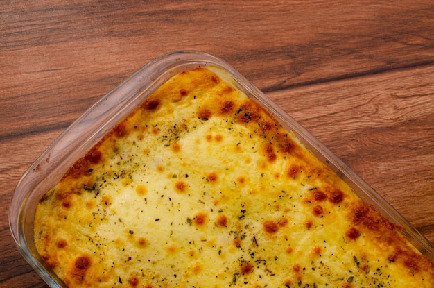 Warme lasagne op houten tafel Vleeslasagne of kiplasagne gebakken in een oven met gesmolten kaas.