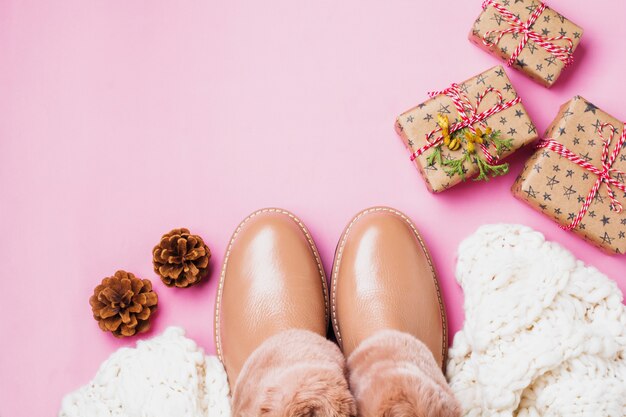 Warme leren damesschoenen met bont, witte sjaal en geschenkdozen op lichtroze achtergrond. concept van het nieuwe jaarseizoen. Bovenaanzicht. Omgaan met ruimte.