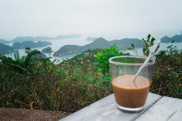 Warme melkkoffie in Vietnam-stijl Ontbijt met een prachtig uitzicht tegen de rotsen die uit het water steken in de zee Halong Bay in Noord-Vietnam kopie ruimte