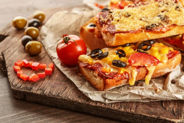 Warme pizza stokbrood met olijven, salami en kaas op houten tafel