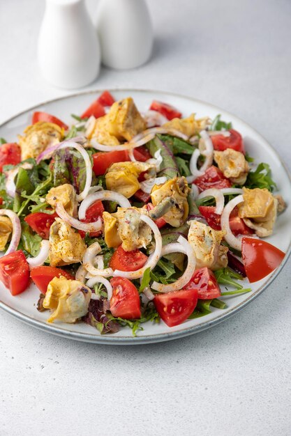 Warme salade met rapan slakken tomaten uien bladgroenten en olijfolie Traditionele salade met zeevruchten Closeup selectieve focus